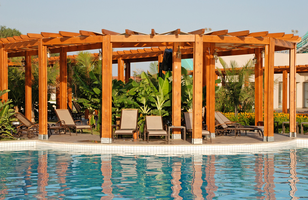 resort swimming pool, wood pergola and deck chairs